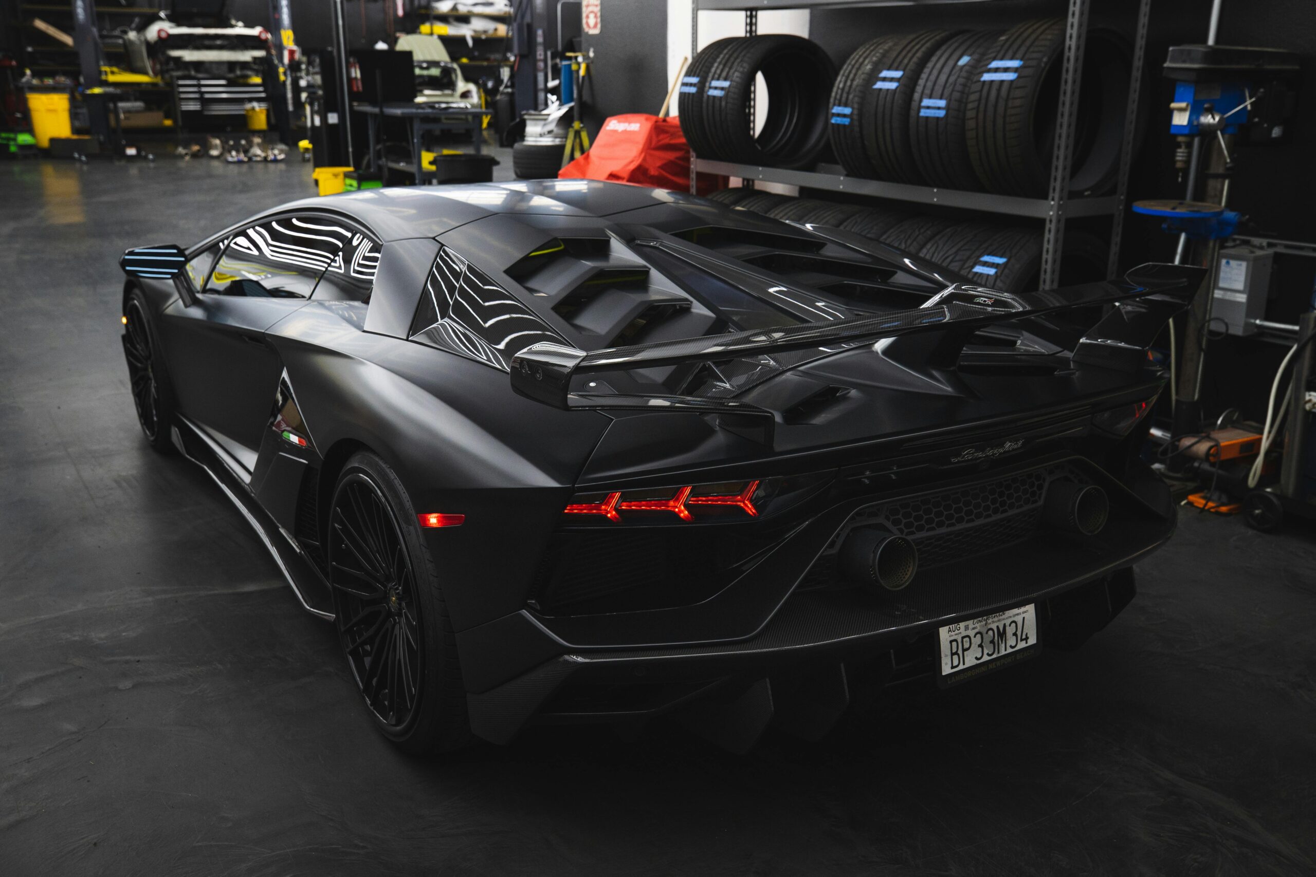 Sleek black Lamborghini Aventador SVJ parked indoors, showcasing luxury and power.